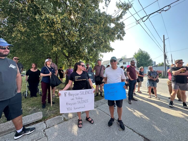 Two people holding some protest signs. 