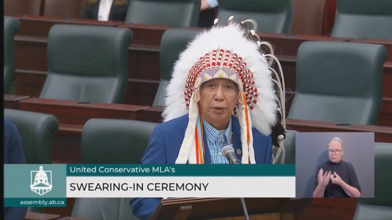 An Indigenous chief in a traditional headdress speaks at the UCP swearing-in ceremony.