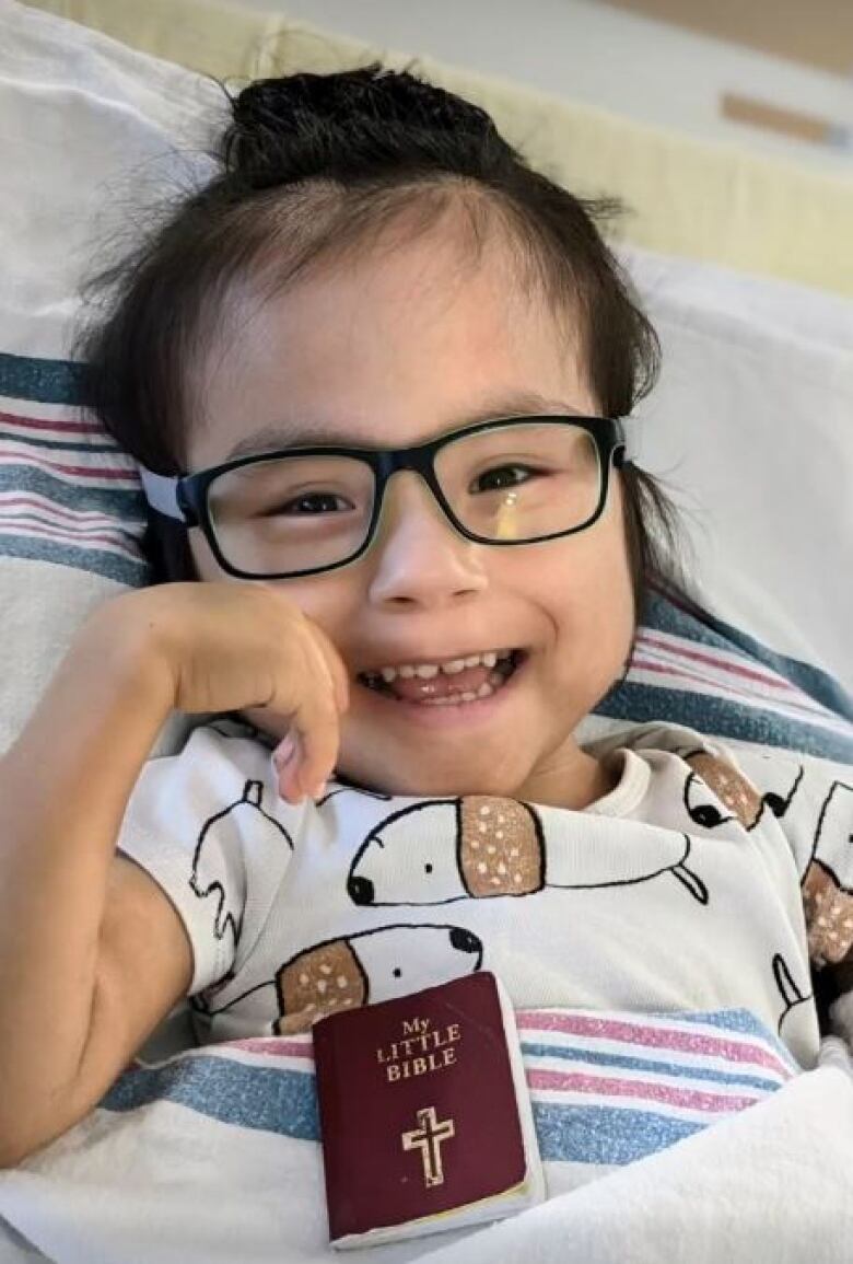 A young boy smiles at the camera from his hospital bed. 