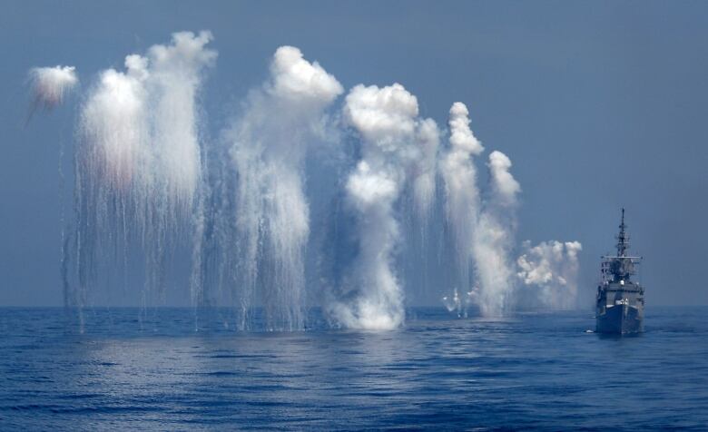 Plumes of smoke and water in background of a ship 