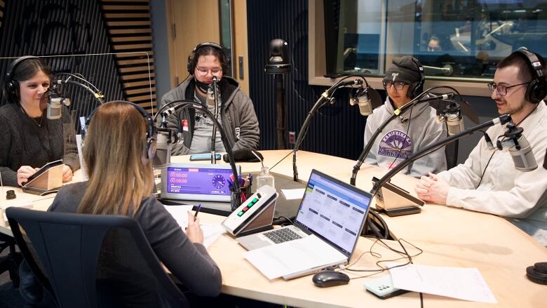 Four guests sit around a table in a radio studio.