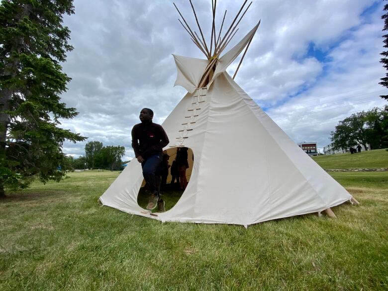 A person emerges from a tipi.