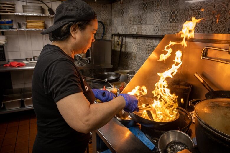 A woman wields a fiery wok