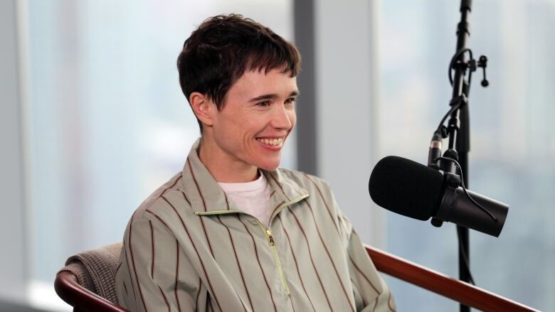 A smiling man sitting in front of a microphone.