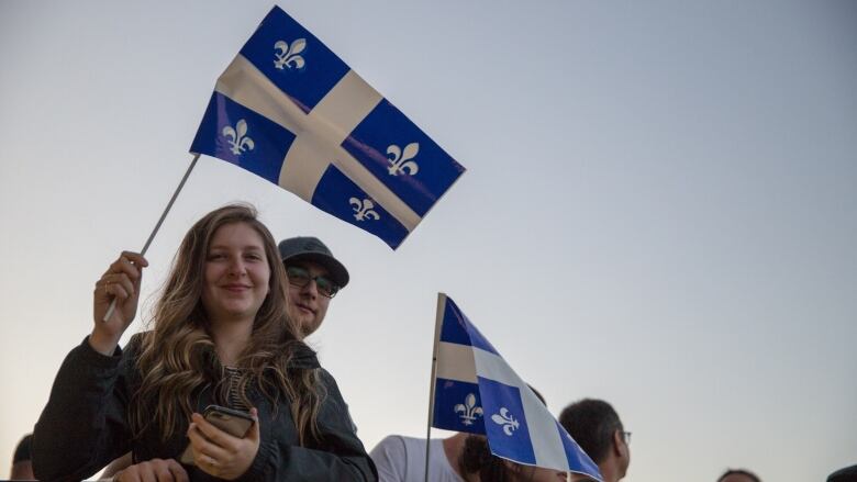 Young people at sunset with Quebec flags.