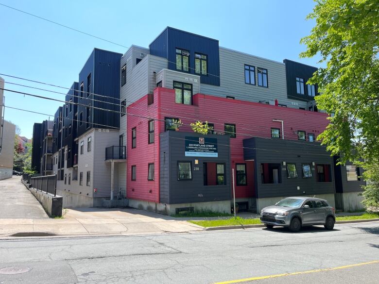 A red, black, and grey modern apartment building is shown. 