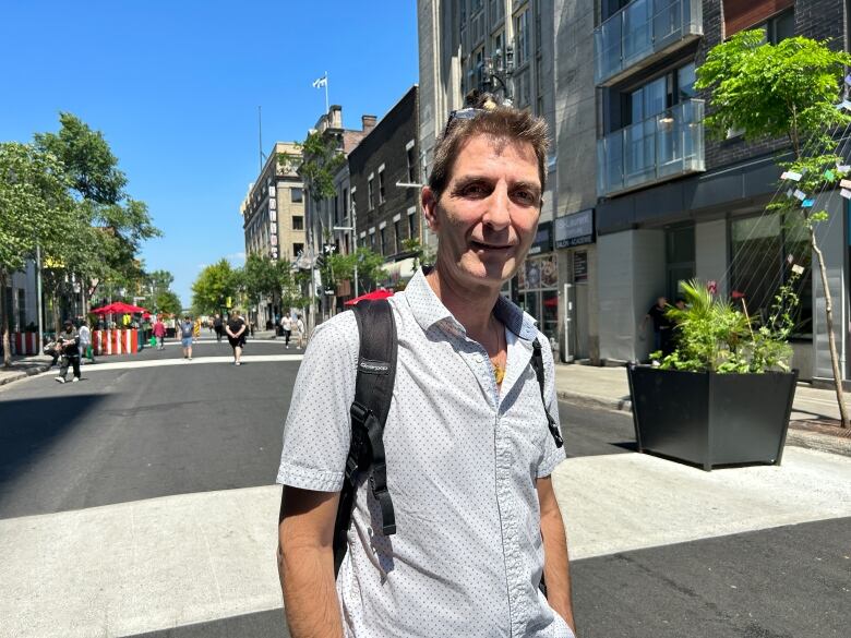 Man stand outside under the sun in Montreal's Village and is posing for the camera. 