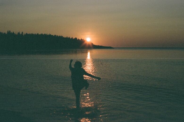 A man is shown from behind at sunset at a beach in Digby County, N.S.