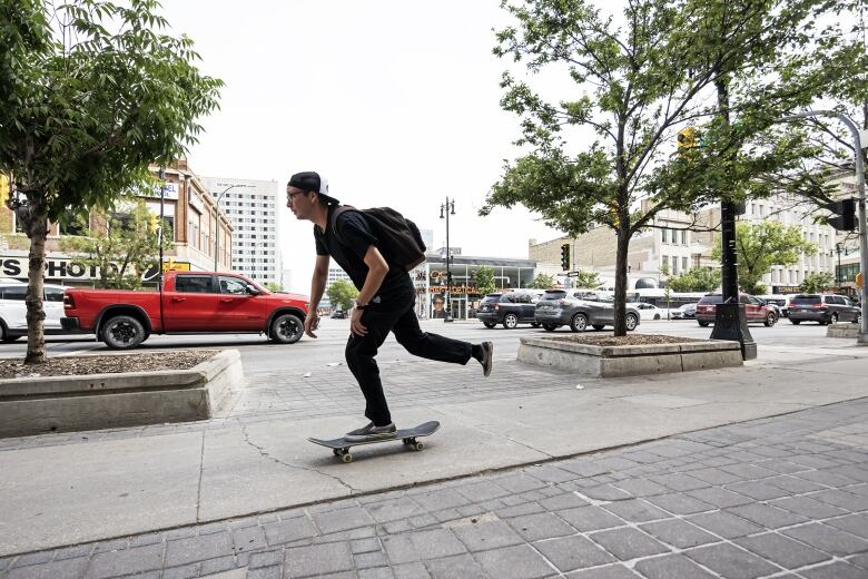 A man skateboards down the street in downtown Winnipeg. 