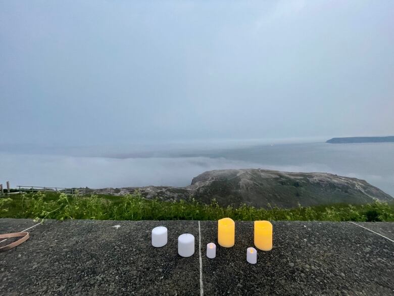 Five candles sit on a marble barricade. The Atlantic Ocean is in the background.