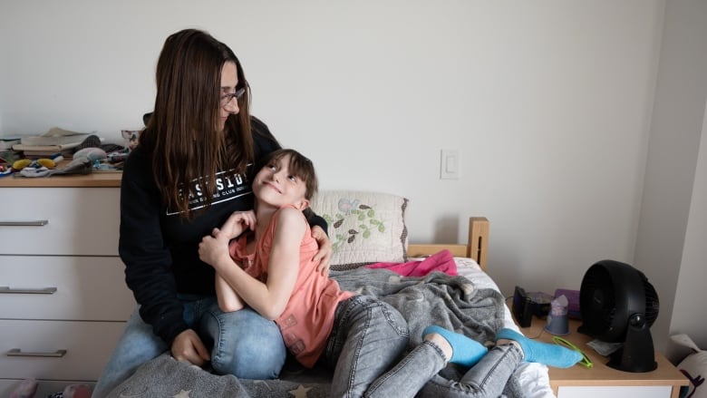 A mother and daughter snuggle on a bed at a recovery centre.