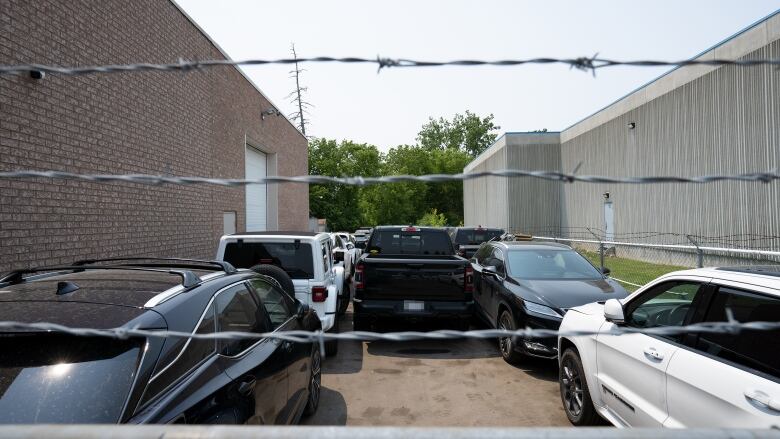 Cars behind barbed wire.