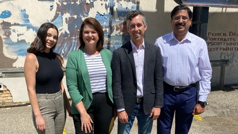 Opposition NDP Leader Carla Beck, second from left, stands with three NDP byelection candidates after a media conference on Friday. The candidates Kaitlyn Stadnyk (far left), Jared Clarke (second from right) and Noor Burki (far right)