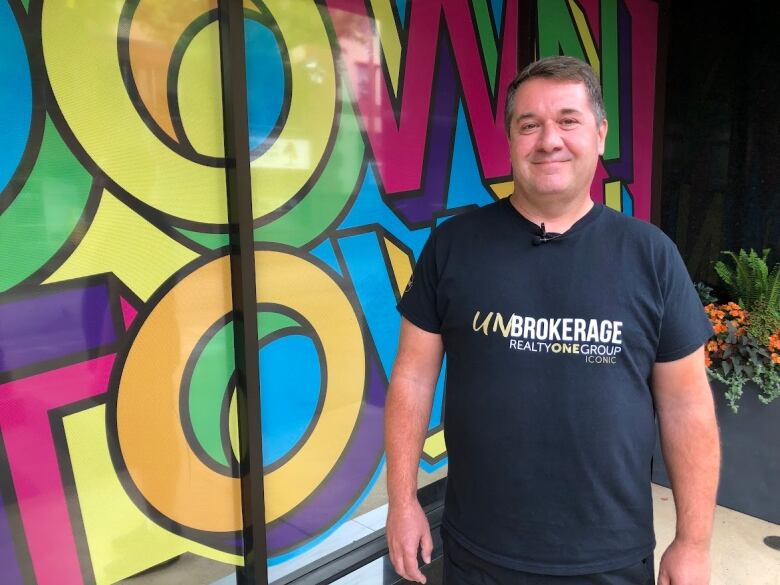 a man in a black shirt stands in front of a multicolored background