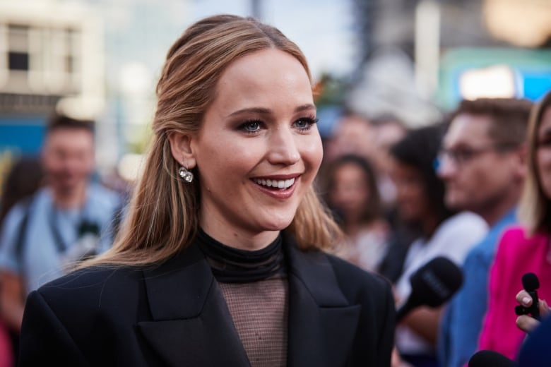 A blond woman wearing a dark blazer smiles.