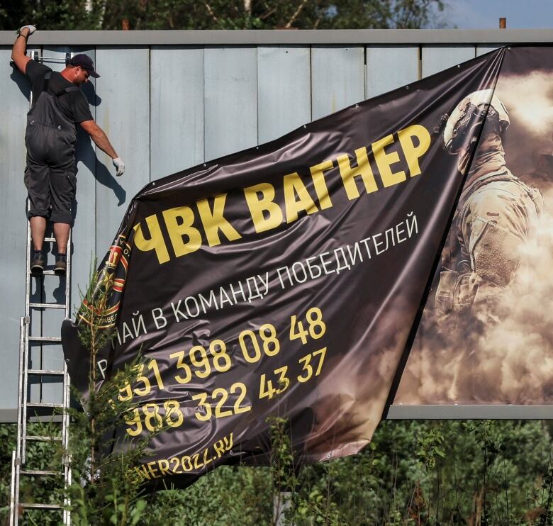 A worker removes a sign advertising the services of Yevgeny Prigozhin's Wagner group in St. Petersburg, Russia.