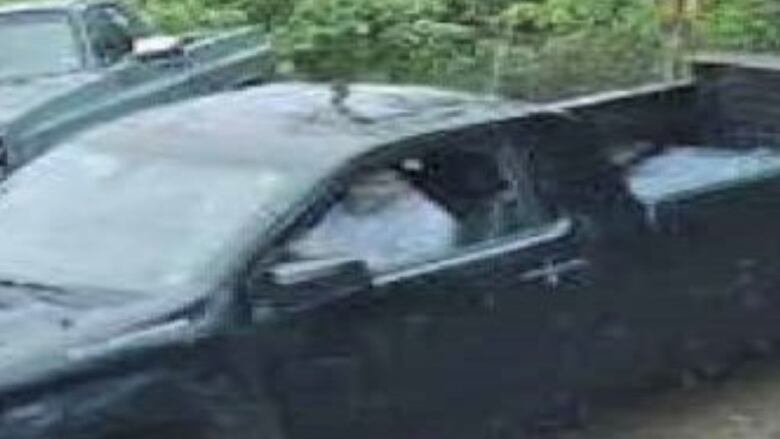 A grainy image of a person sitting in a pickup truck.