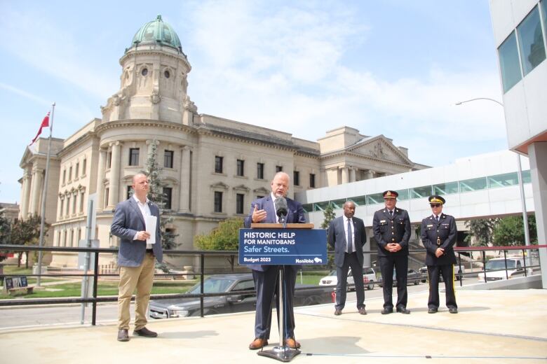 Politicians and police stand by a podium during a government announcement.