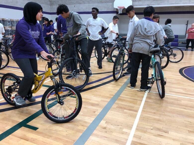 A group of students in a school gym with bikes.