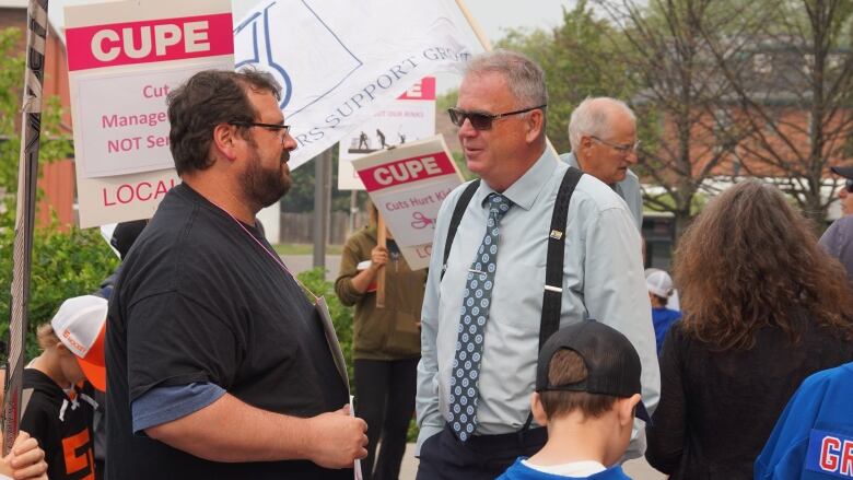 Two men speak in the middle of a crowd. 