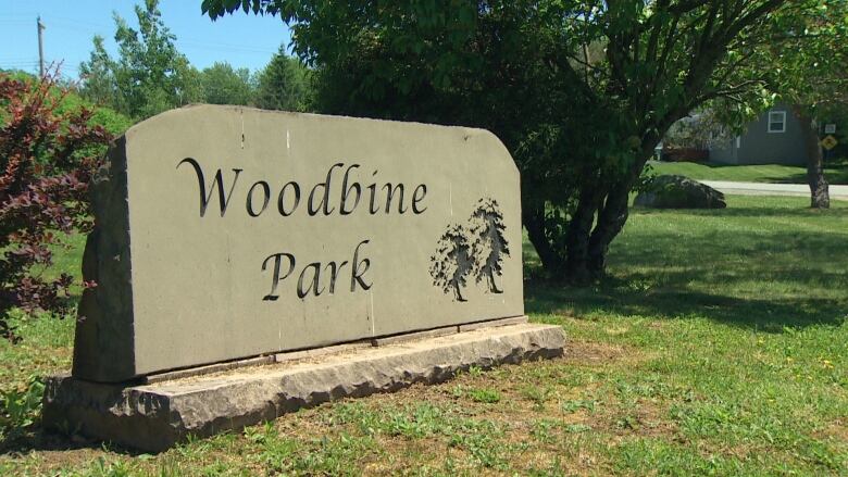 Woodbine Park is carved into a grey rock to serve as a sign at the entrance to the community