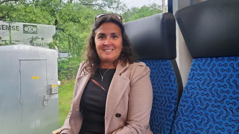 A woman sits on a train, smiling