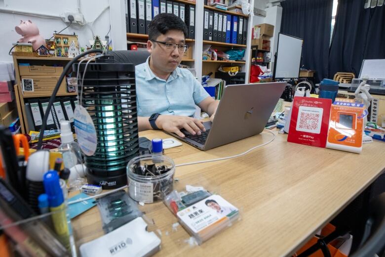 A man types on a laptop in an office.