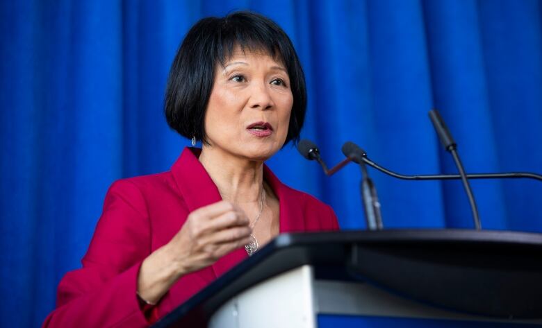 Portrait of Olivia Chow at a podium microphone. 