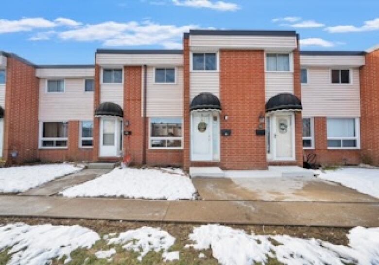 A picture of a town home with snow on the lawn. 