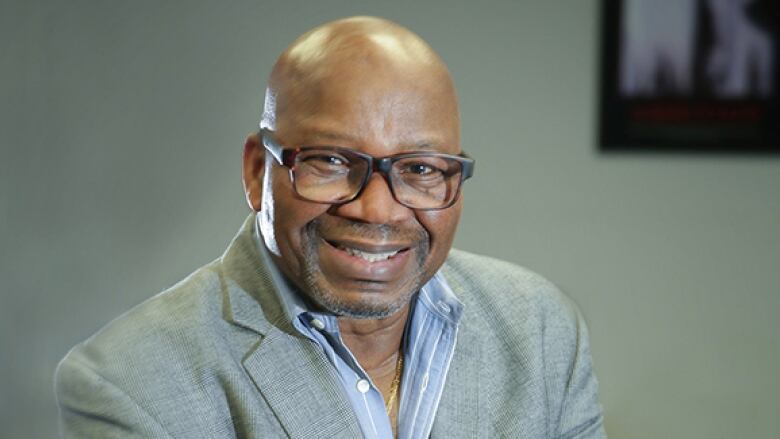 A man with glasses smiles for the camera.