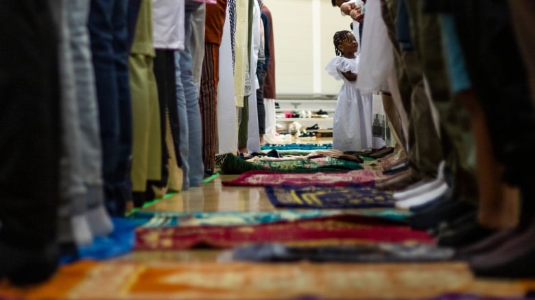 A young girl stands by muslim prayer mets surrounded my men praying during Eid al-Adha celebrations.