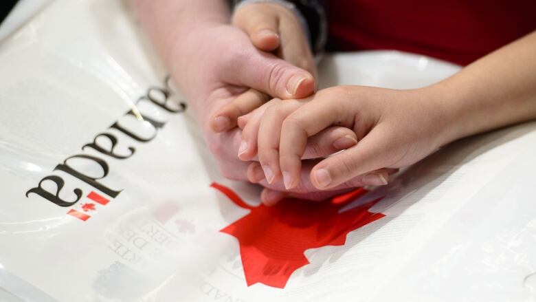 A mother and daughter hold hands during citizenship ceremony in Ottawa on Wednesday, April 17, 2019. Statistics Canada says the country welcomed more than 145,000 immigrants during the first the months of the year. THE CANADIAN PRESS/Sean Kilpatrick