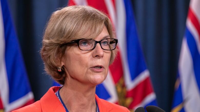 A white woman with short brown hair addresses a news conference.