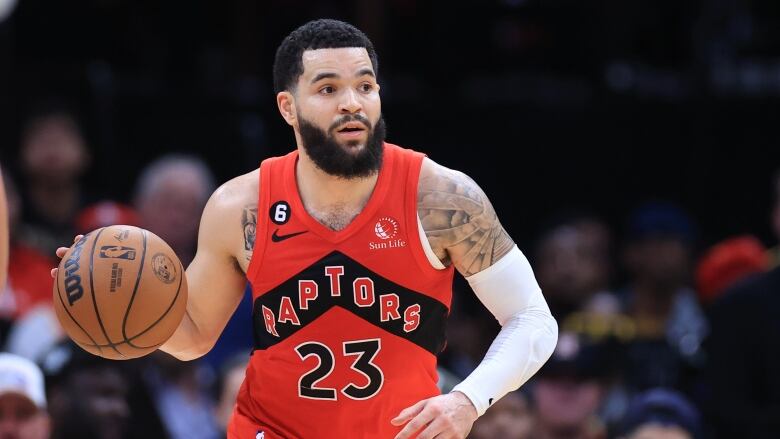 A basketball player looks ahead as he dribbles the ball.