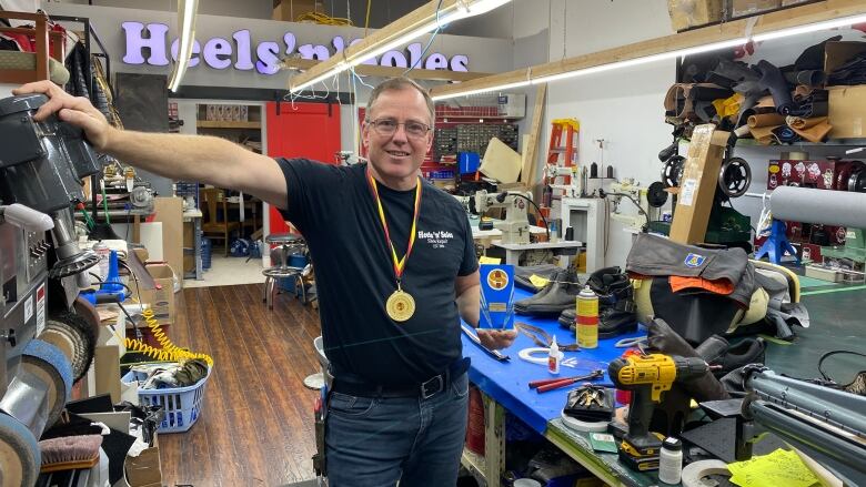 A man wearing a gold medal while standing in a shoe repair shop/