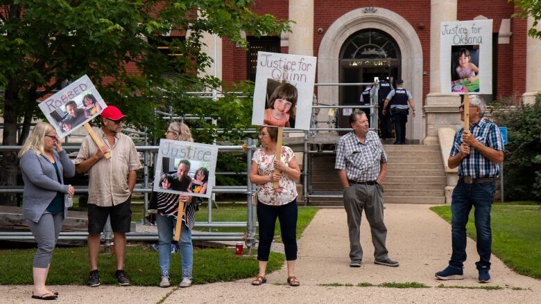 People holding placards with photos on them and words including 