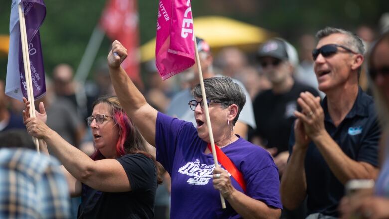 A crowd of people with flags raise their arms and clap. 