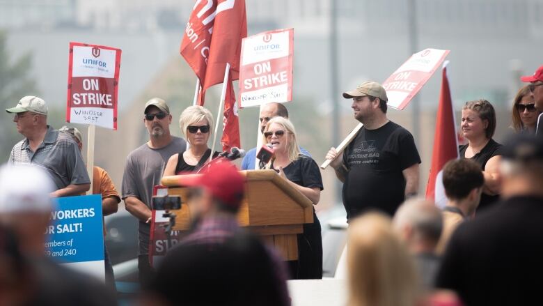 A woman at a podium pictured through a crowd of people