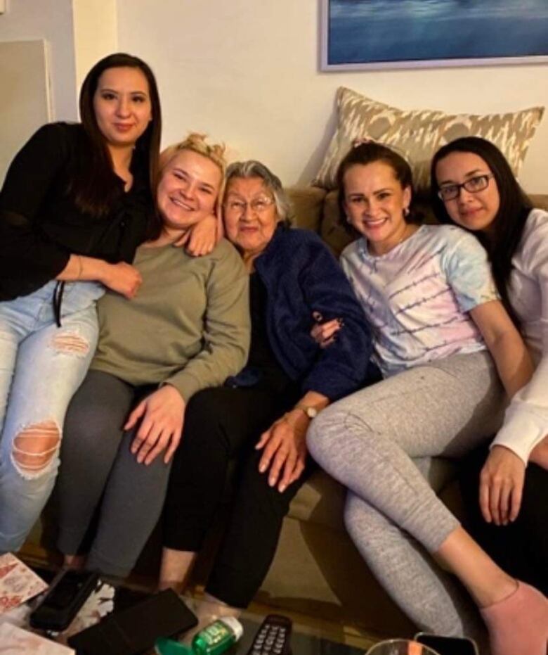 A woman sits with multiple family members on a couch. 