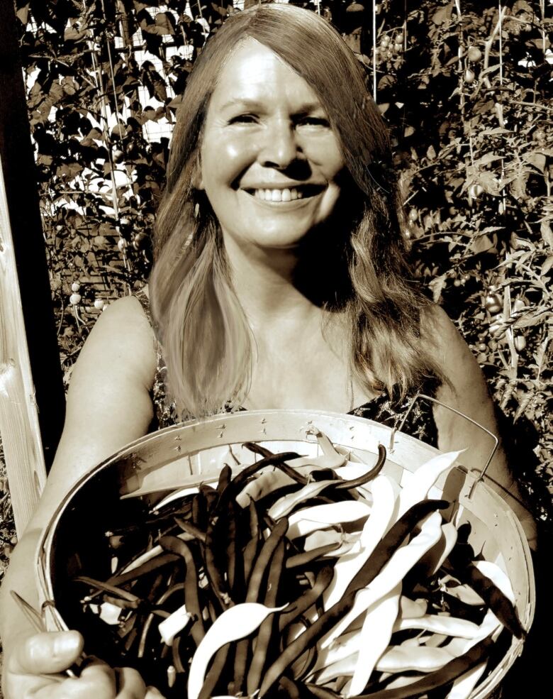 A woman holds a bundle of beans in a sepia coloured photo. 