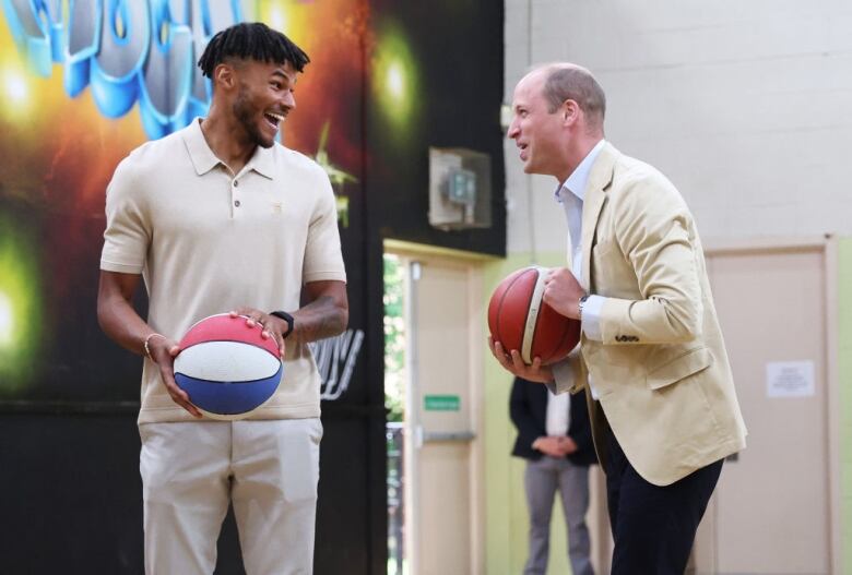 Two people holding basketballs talk and laugh with one another.