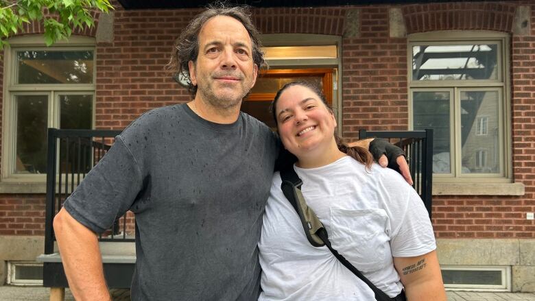 Two people stand in the street.