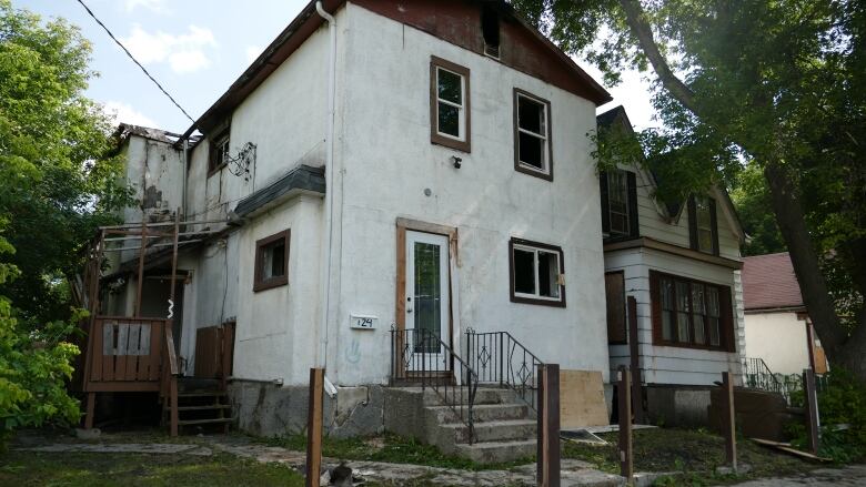 A home with broken windows and burn marks on the outside.