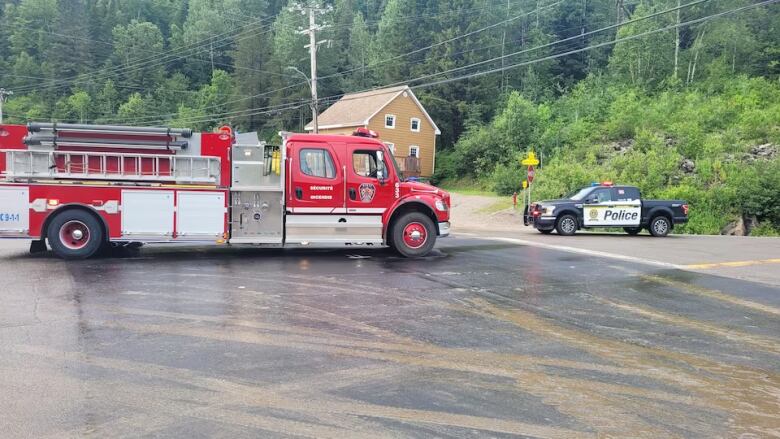 A fire truck and a police car are parked on the street. 