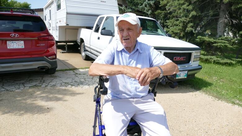 A man sits on a walker chair. 