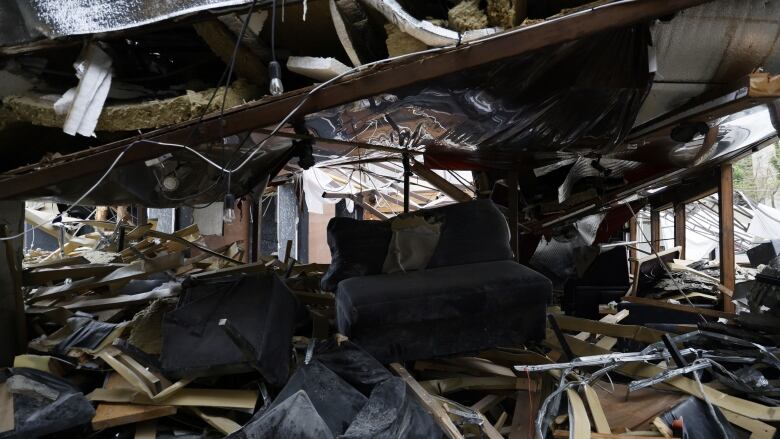 The interior of a building destroyed is shown, with pieces of wood and damaged furniture shown.