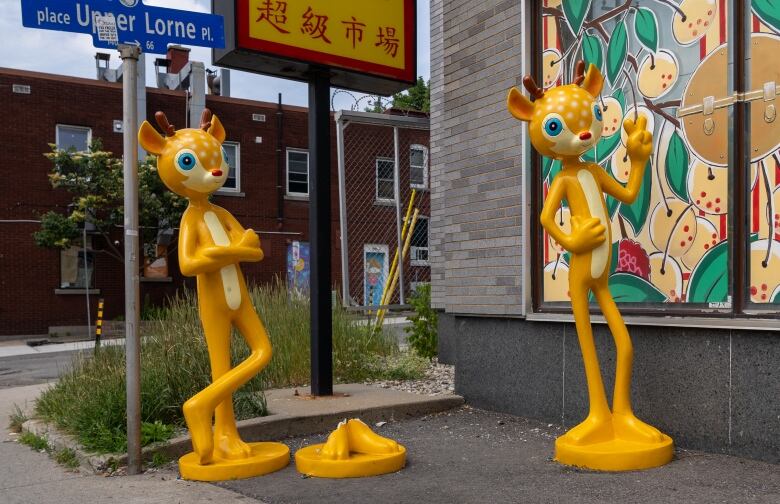 Three yellow statues of cartoon deer, one of which is broken off at the base.