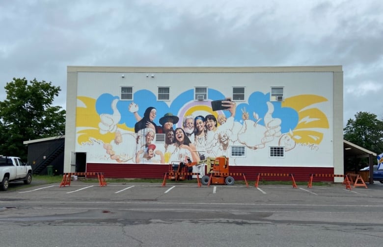 A shot of the side of a building with a mural depicting smiling people on it.