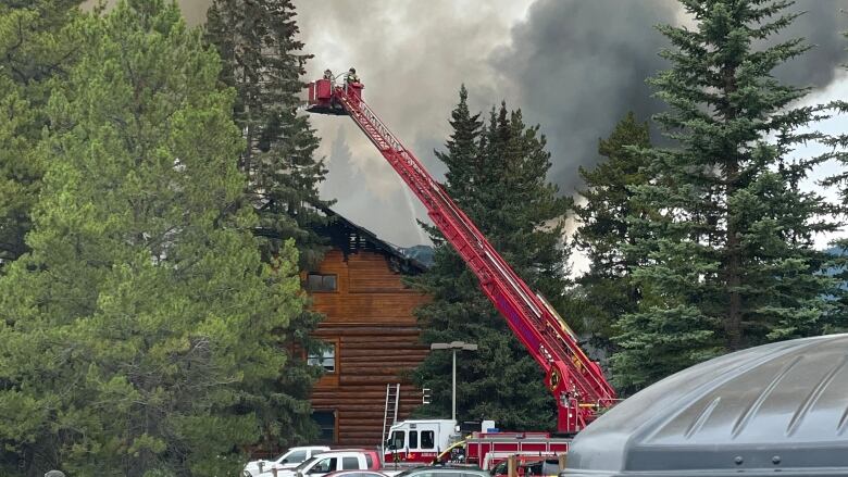 A log building on fire is pictured with smoke in the background.