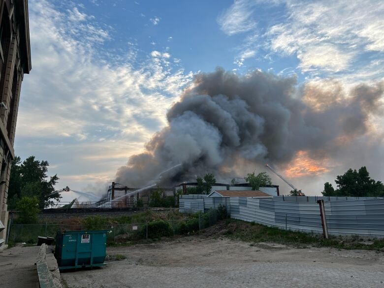 Plumes of smoke rise up from an industrial building on fire.